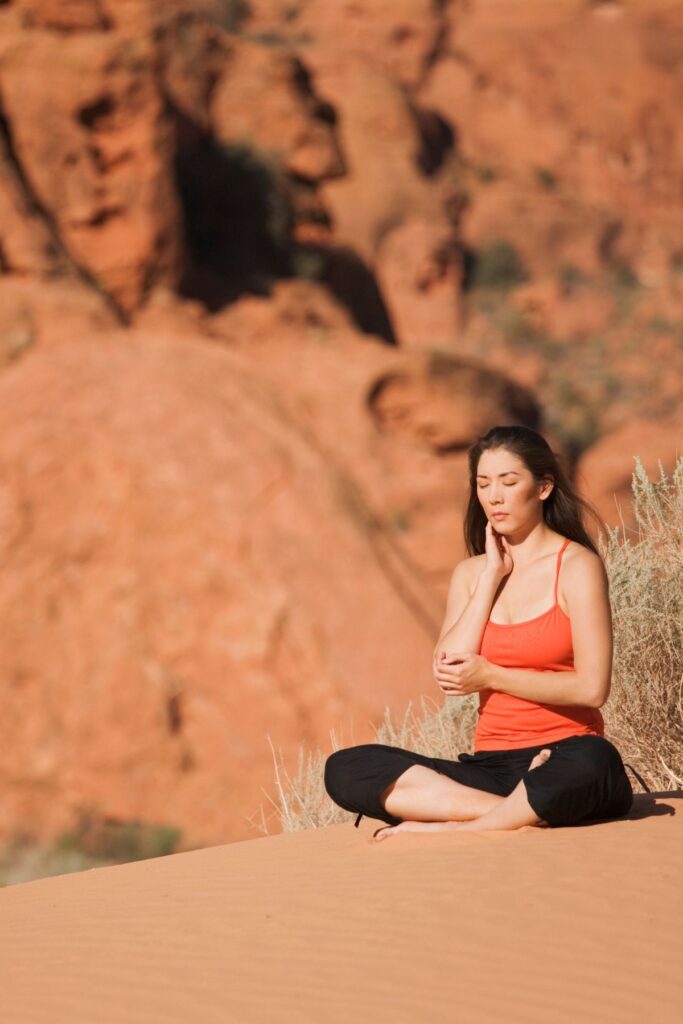 Woman with dark hair meditating in the desert.