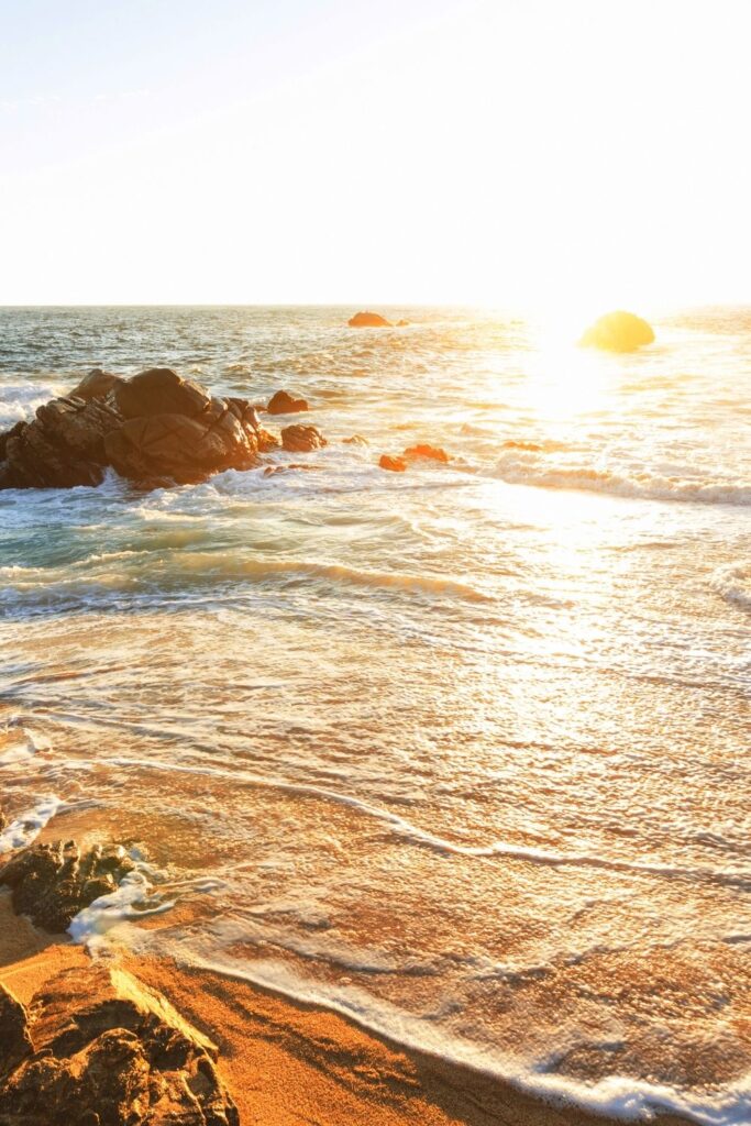 Sunny ocean image with water and rocks.