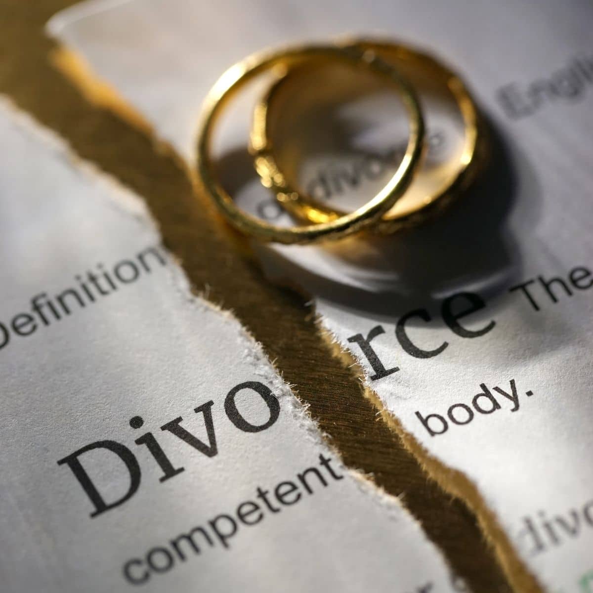 An image of divorce papers with gold wedding bands laying on top.